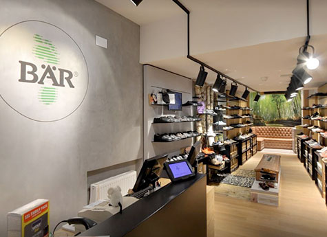 Ein heller und modern gestalteter Schuhladen mit Regalen voller Schuhe und einem eleganten Empfangstresen.