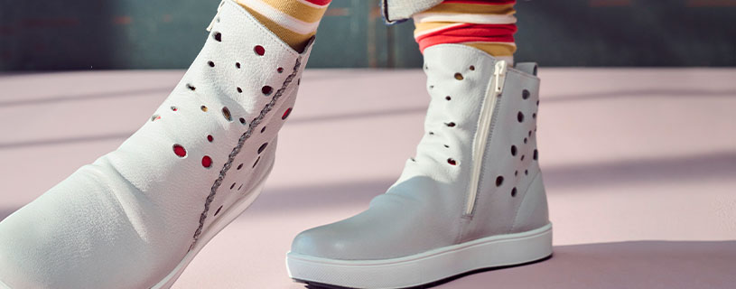 Weiße Stiefeletten mit Lochmuster und Reißverschluss auf rosa Boden