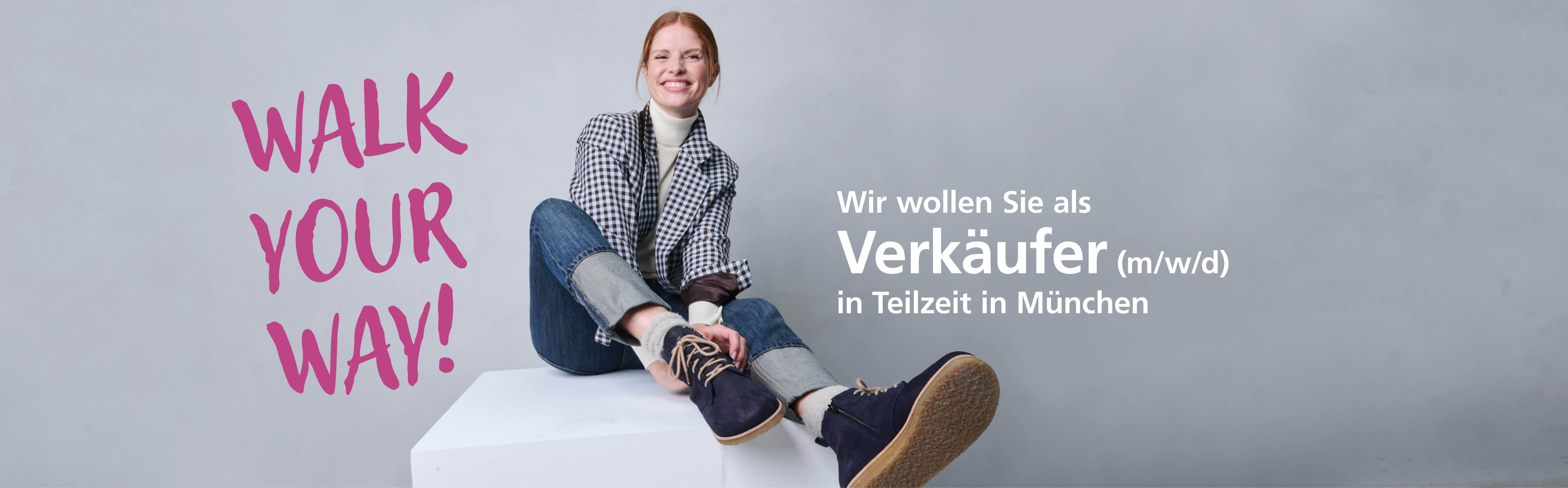 Person sitzt lächelnd auf einer weißen Box, daneben der Text 'Walk Your Way!'. Gesuch: Verkäufer (m/w/d) in Teilzeit in München.