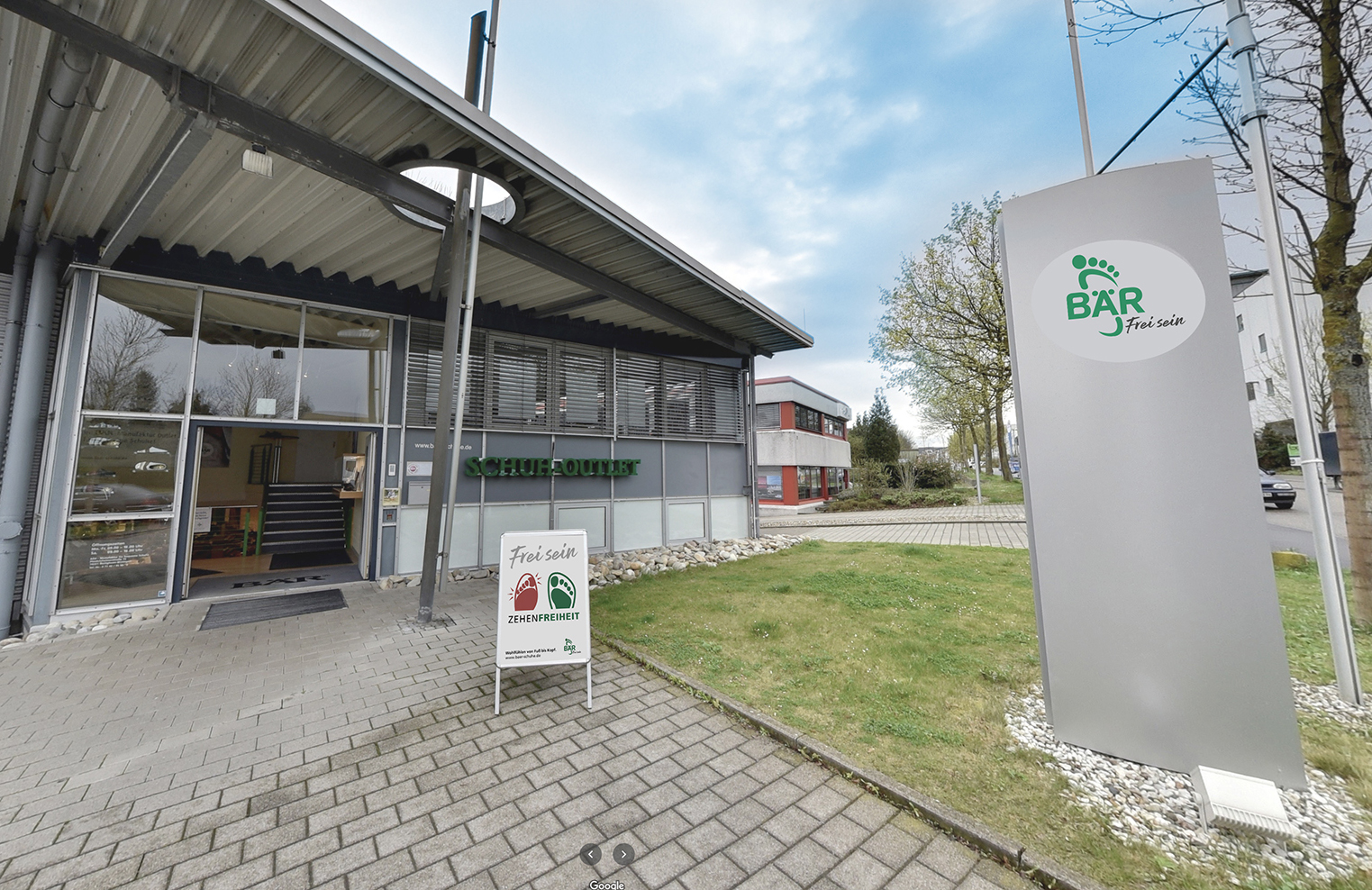 Schuh-Outlet-Gebäude mit BÄR-Werbeschild und Eingang in grüner Umgebung