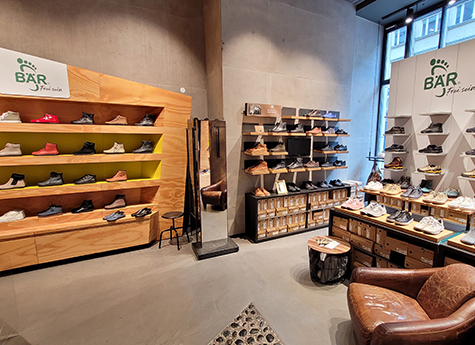 Innenansicht eines Schuhladens mit modernen Regalen voller Schuhe und bequemer Sitzgelegenheit